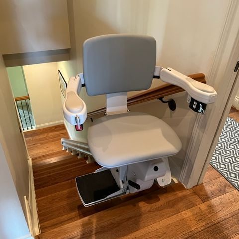 A stair lift with a gray seat and a white railing