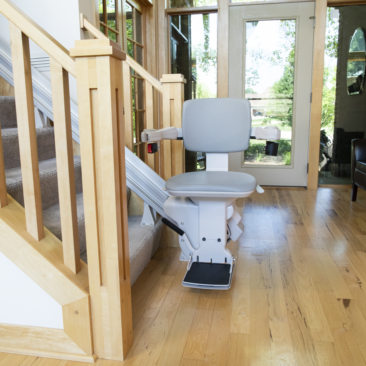 A stair lift with a gray seat and a wooden railing