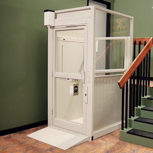 A white elevator is sitting next to a set of stairs.