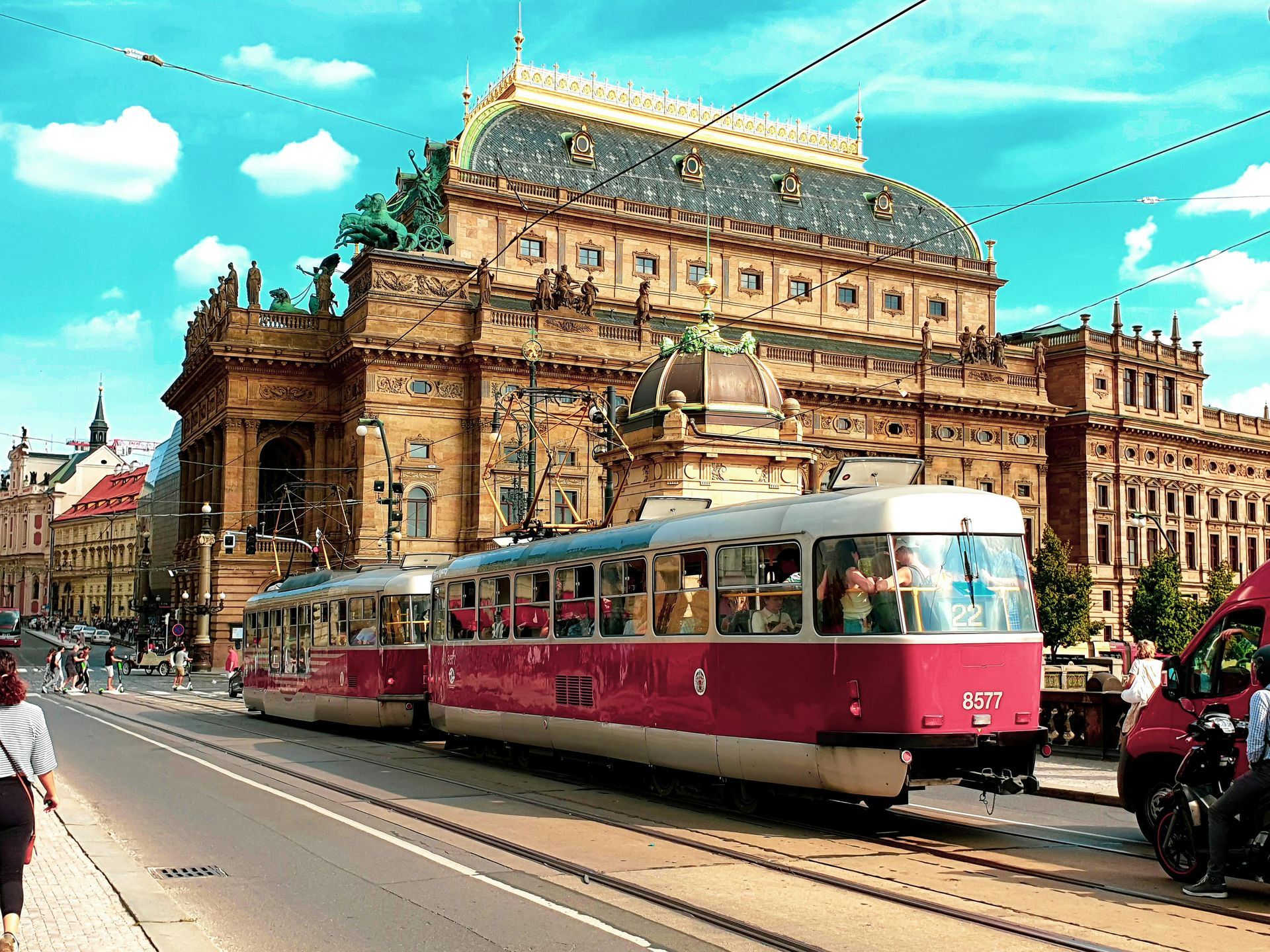 A train is going down the tracks in front of a large building.