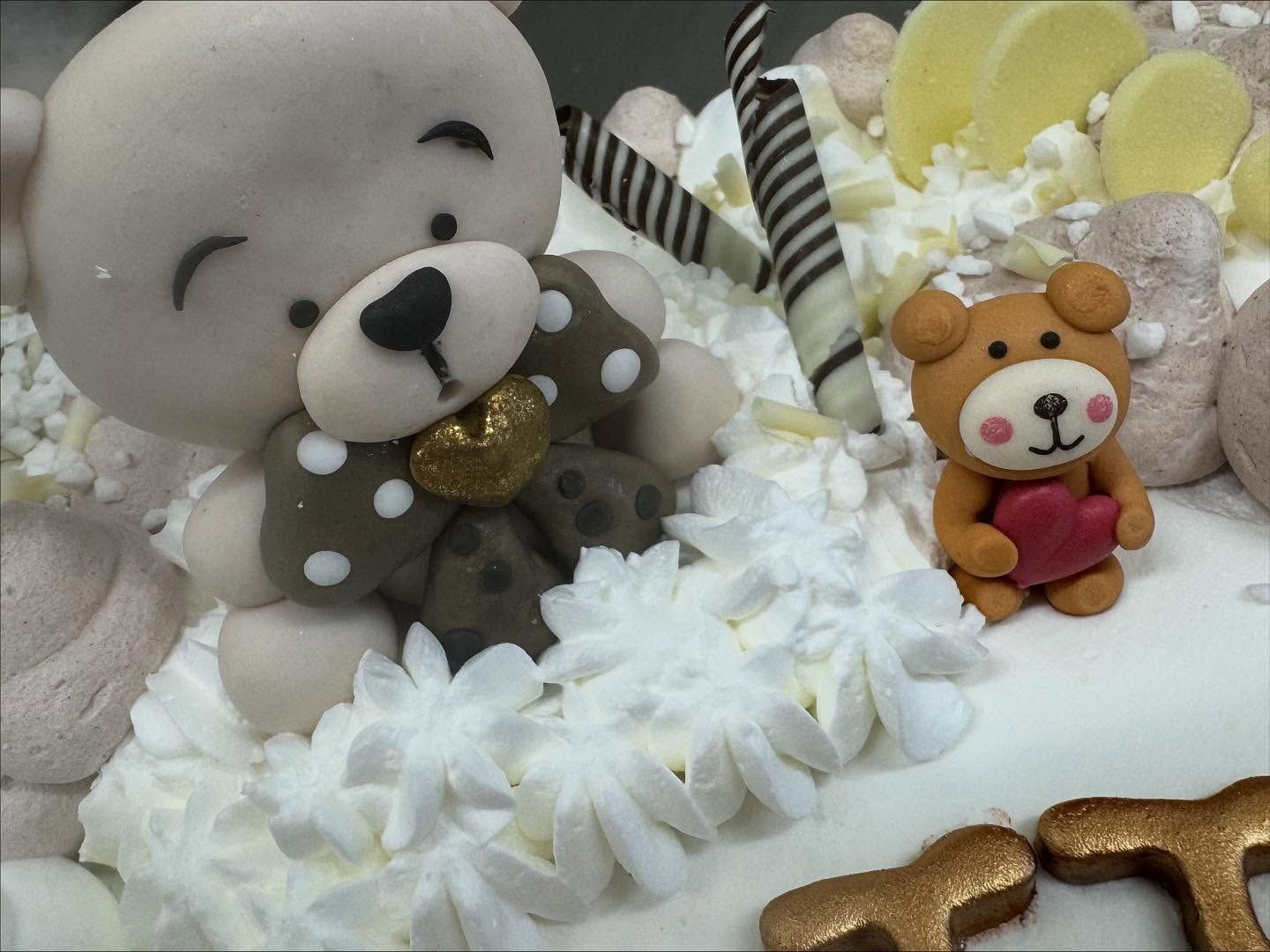 Torta decorata con statuette di orsacchiotti, glassa bianca e dettagli di cioccolato.
