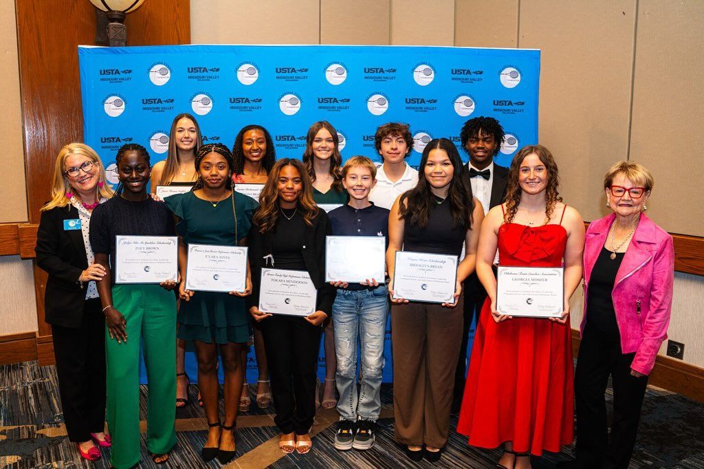 Group of people holding certificates at an awards event in front of a blue backdrop