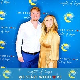 Two people posing at a blue 