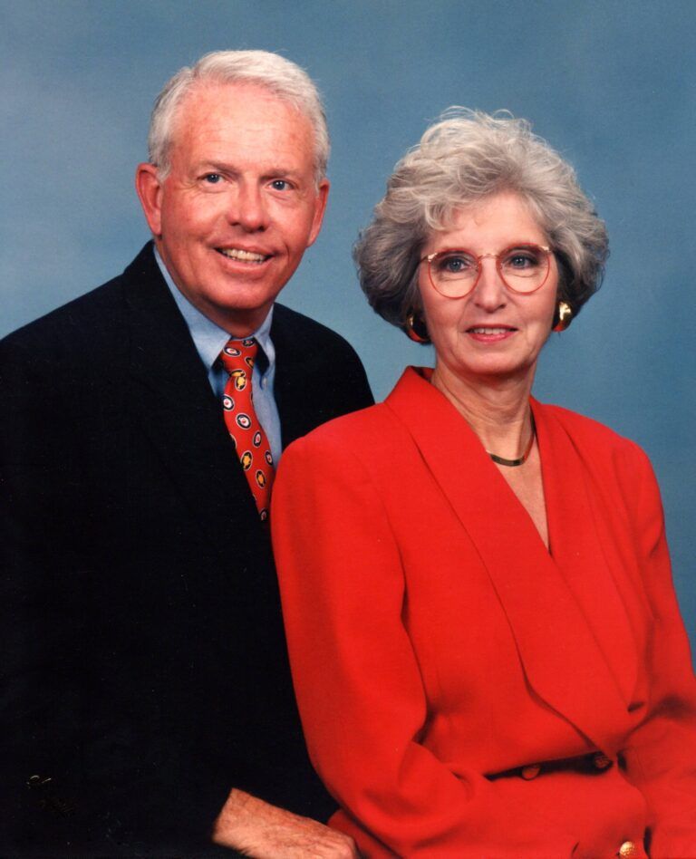 Two formally dressed people posing against a blue studio backdrop