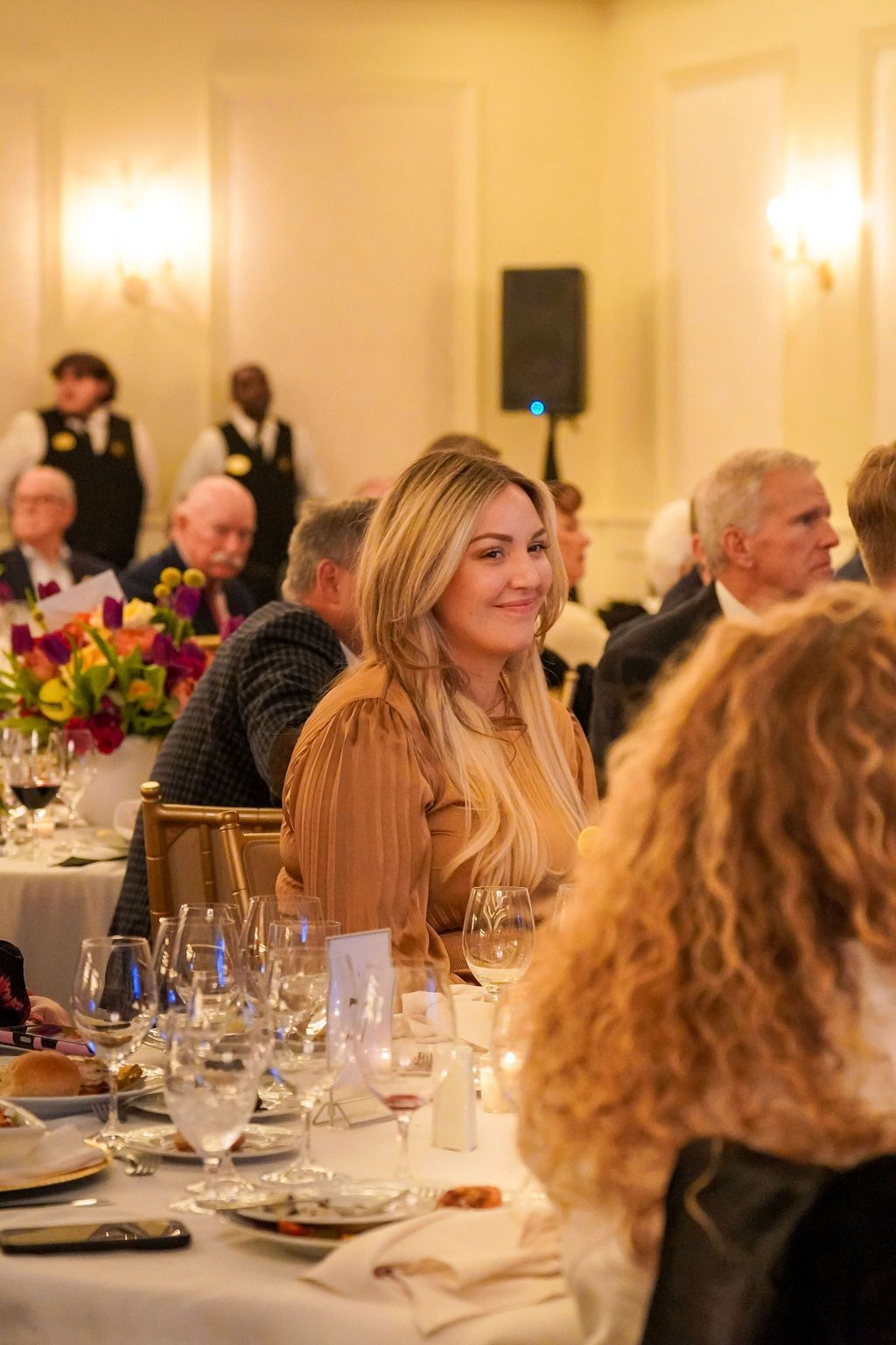 Woman smiling at a banquet table in a warmly lit reception hall