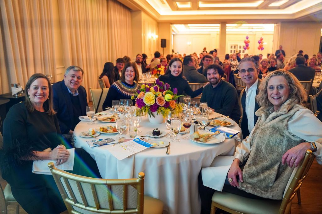 Guests seated around a round banquet table with a floral centerpiece in a warmly lit reception hall