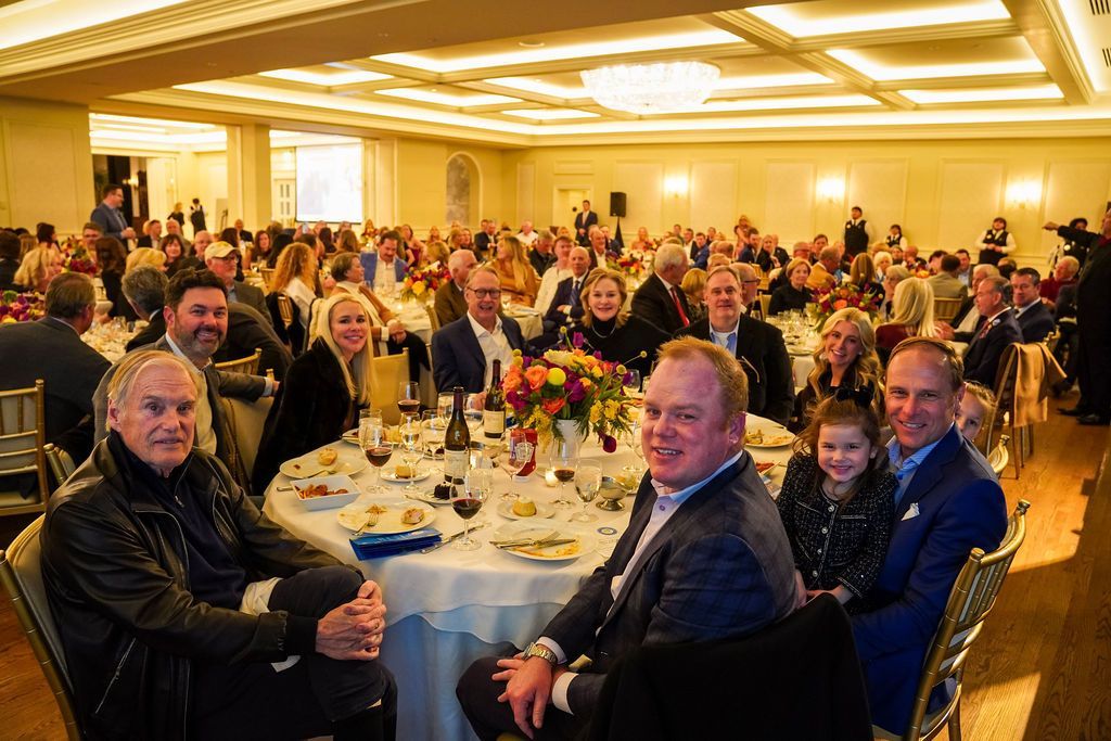 Banquet hall packed with guests seated at round tables under warm lighting