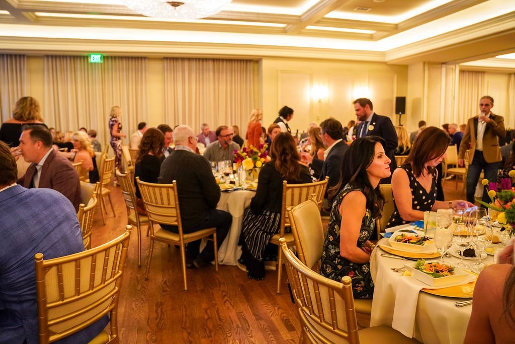 Guests seated at round tables in a warmly lit banquet hall during a formal dinner event