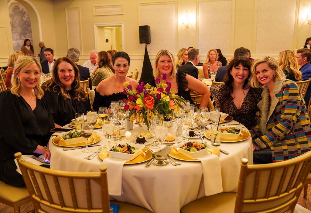 Guests seated at a round banquet table with floral centerpiece in a warmly lit event hall