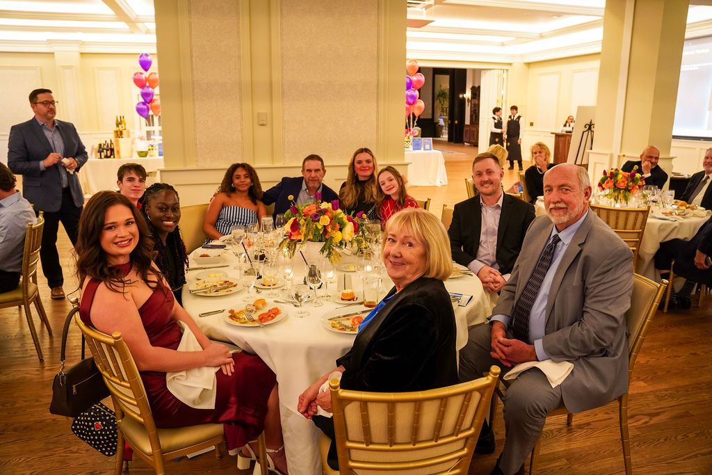 Guests seated around a banquet table at an indoor reception, smiling and chatting