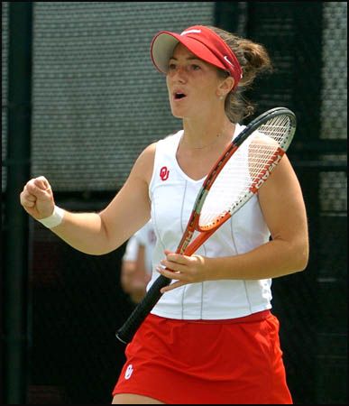 Tennis player in red cap and skirt, holding a racket and cheering on the court.