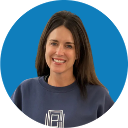 Smiling person in a dark sweatshirt against a bright blue background