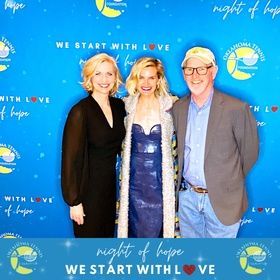 Three people posing at a blue “Night of Hope” event backdrop, smiling in formal attire