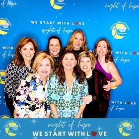 Seven women smiling at a blue 