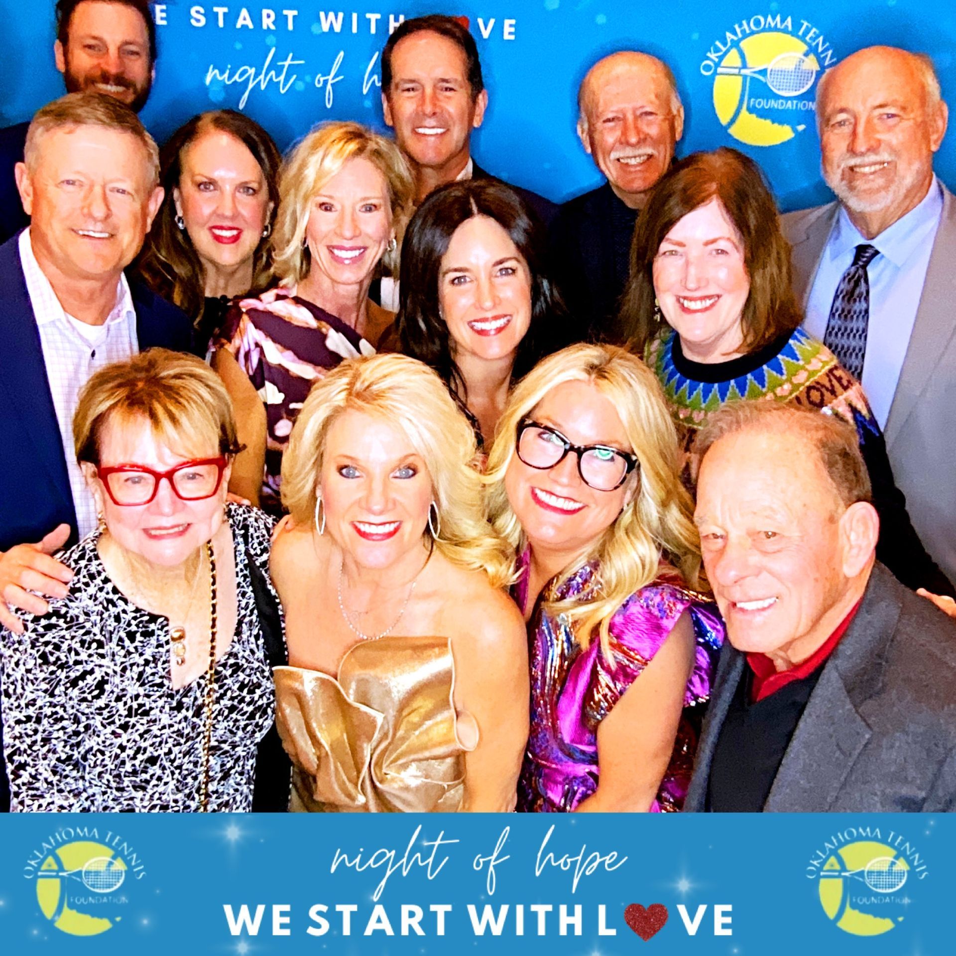 Group of smiling people posing at a “Night of Hope” event backdrop with “We Start With Love” signage
