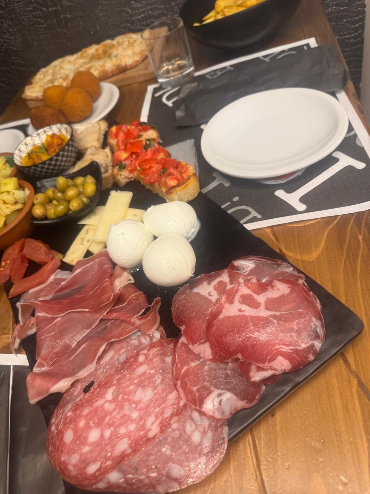 Tagliere di salumi: carni assortite, formaggi, bruschette, olive e antipasti su un tavolo del ristorante.