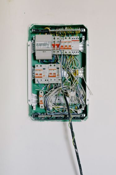 Inside an electrical control box: wires, breakers, and electronic components, with red, yellow, black and blue wiring.