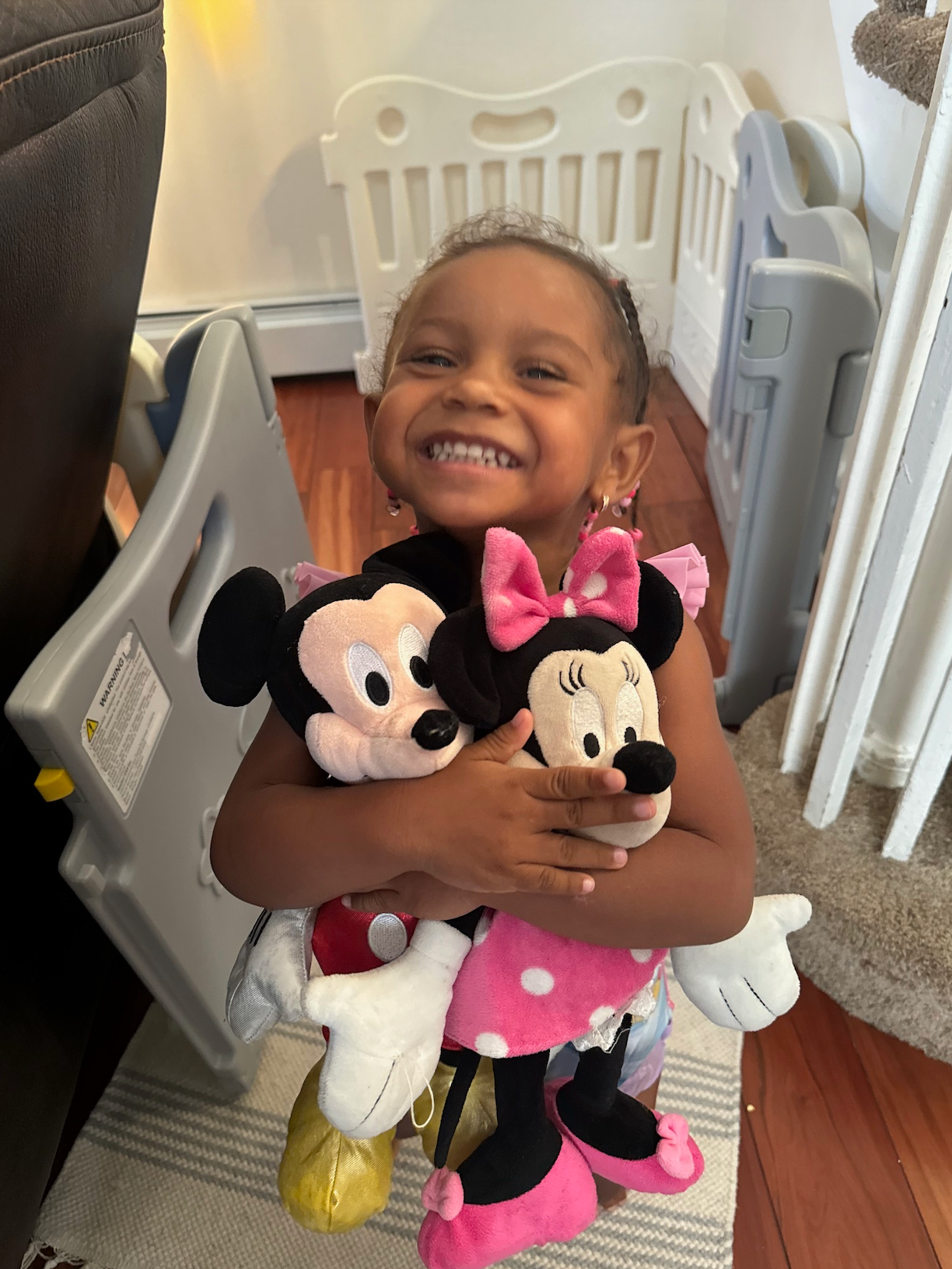 A little girl is holding a mickey mouse and minnie mouse stuffed animal.