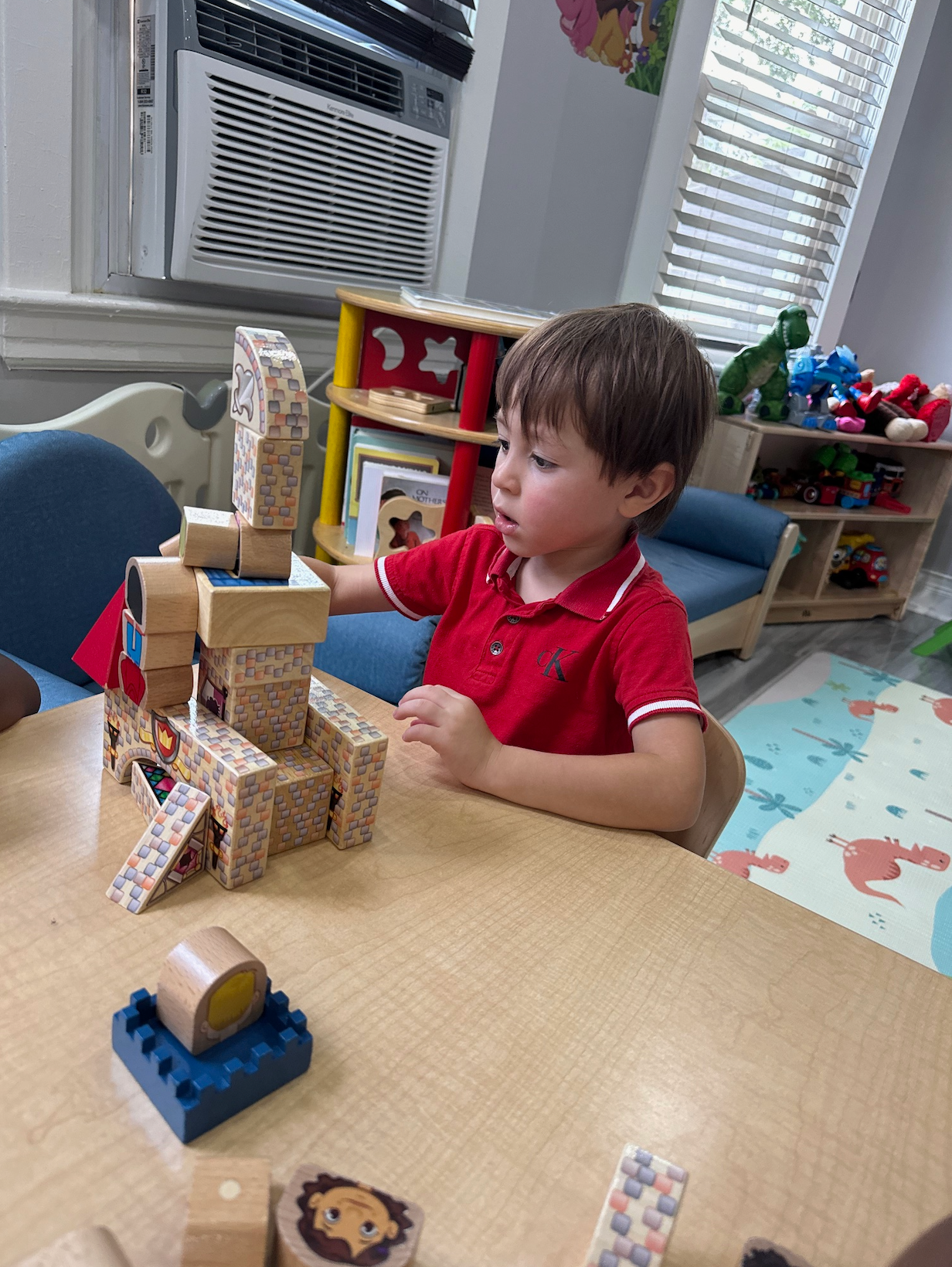 A young boy is sitting at a table playing with wooden blocks.