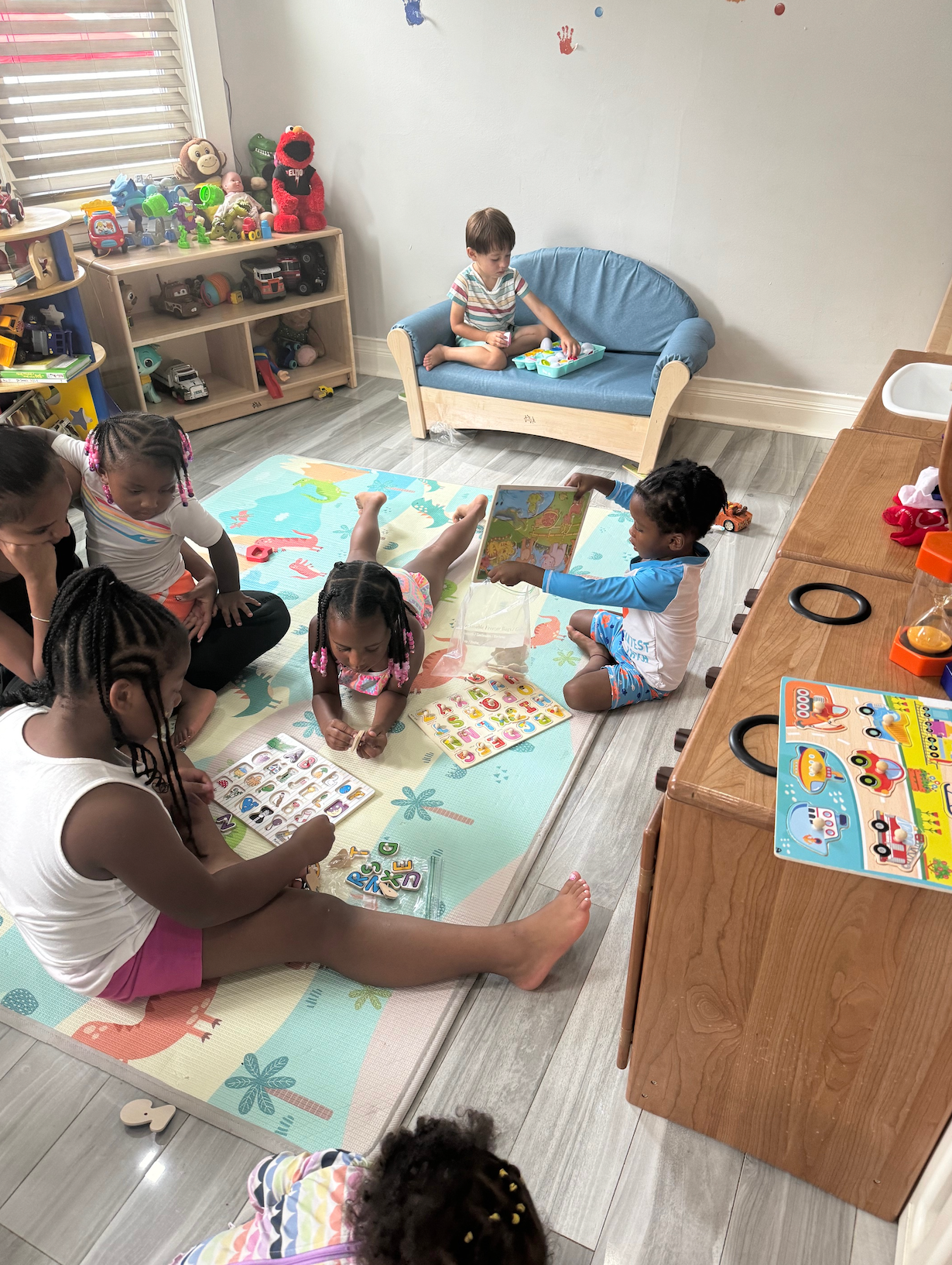 A group of children are sitting on a rug in a room.