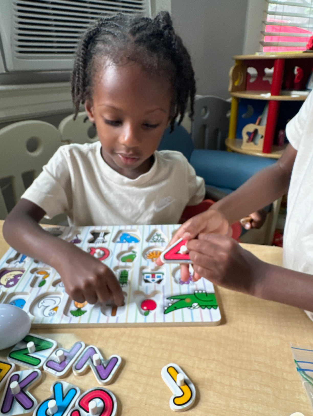 A little girl is playing with a puzzle with letters on it