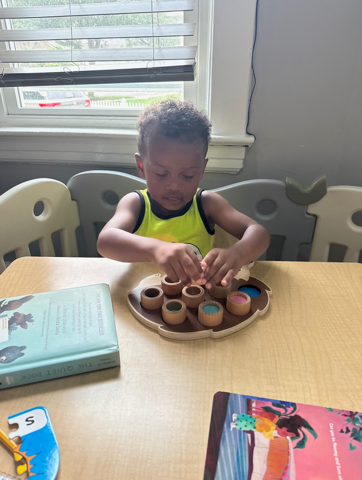 A young boy is sitting at a table playing with wooden toys.