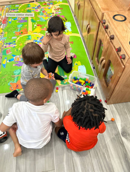 A group of children are sitting on the floor playing with toys.