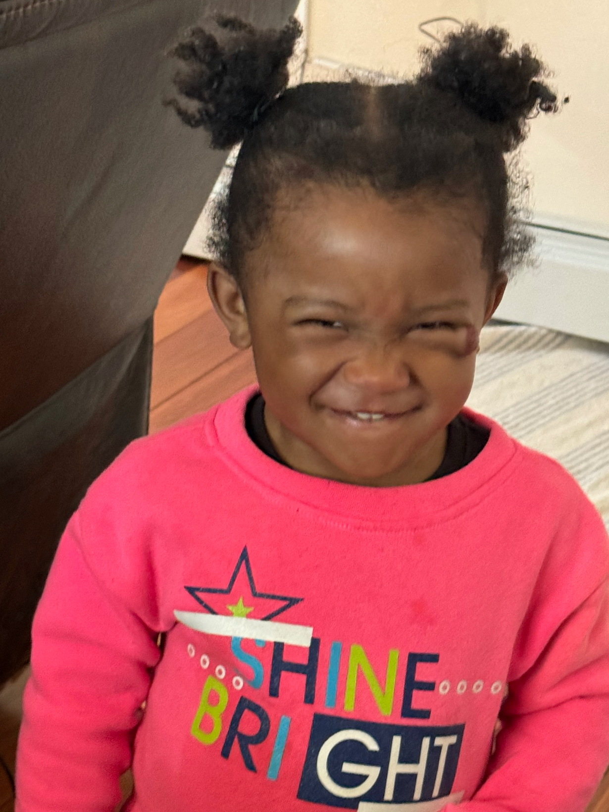 A little girl wearing a pink shirt that says shine bright