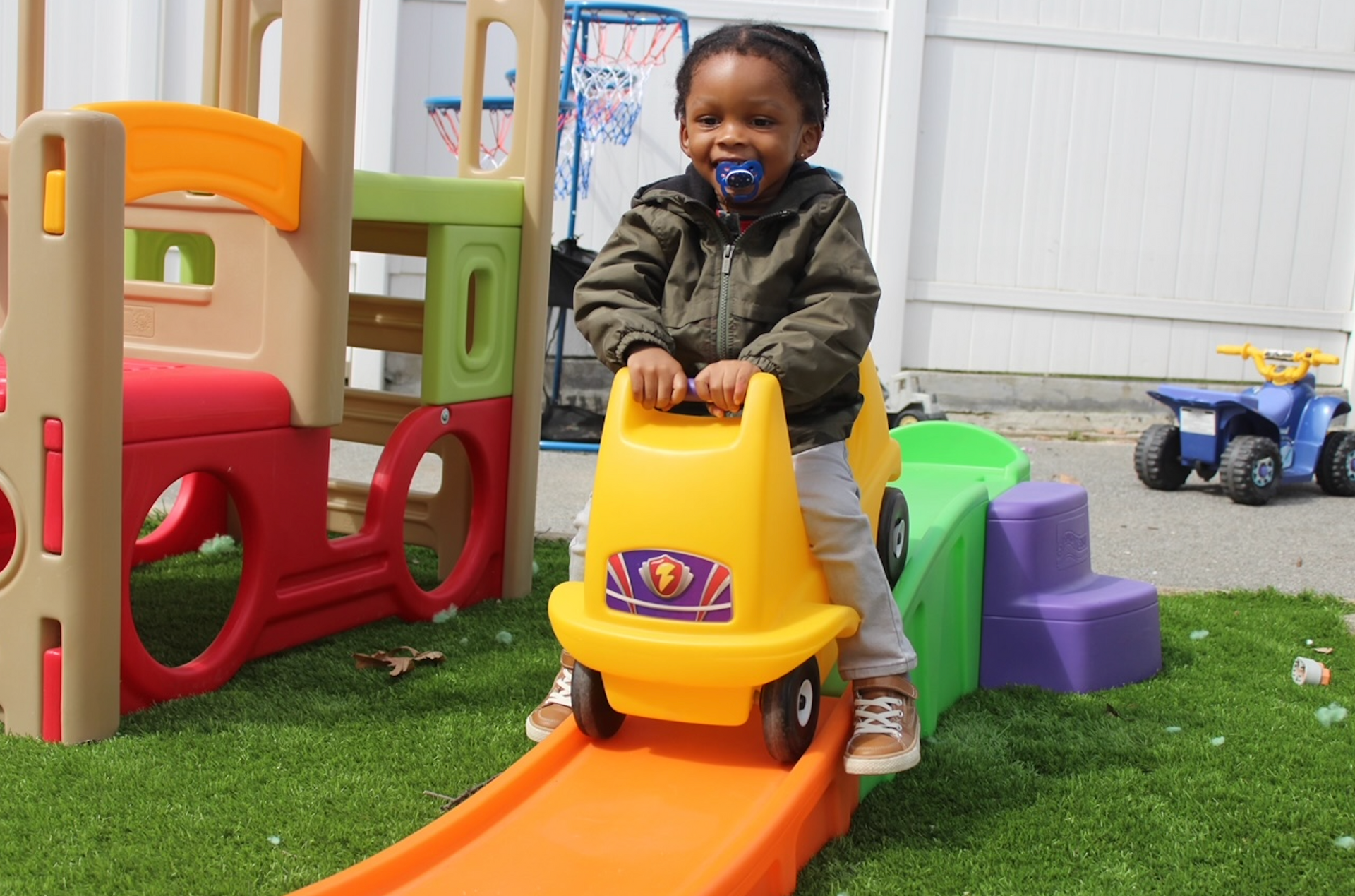 A young boy is riding a yellow toy car on a roller coaster.