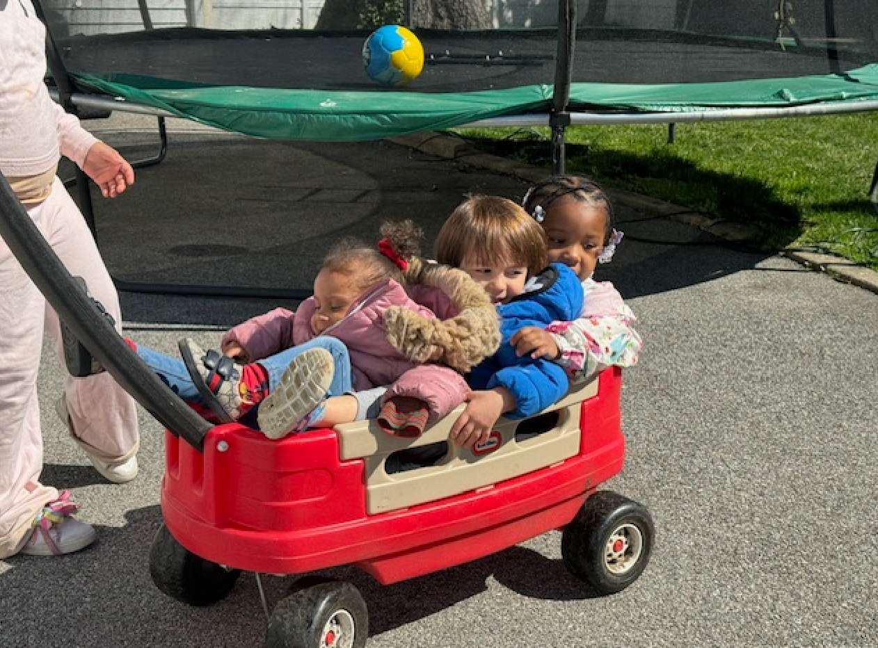 A group of children are riding in a red wagon.