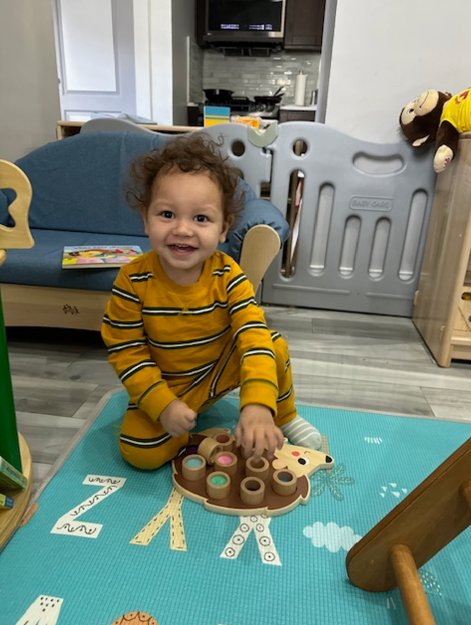 A little boy is sitting on the floor playing with a toy hedgehog.
