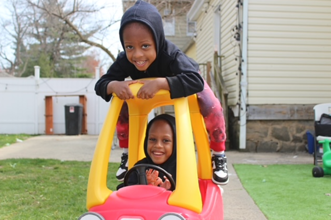 A boy and a girl are playing in a toy car.