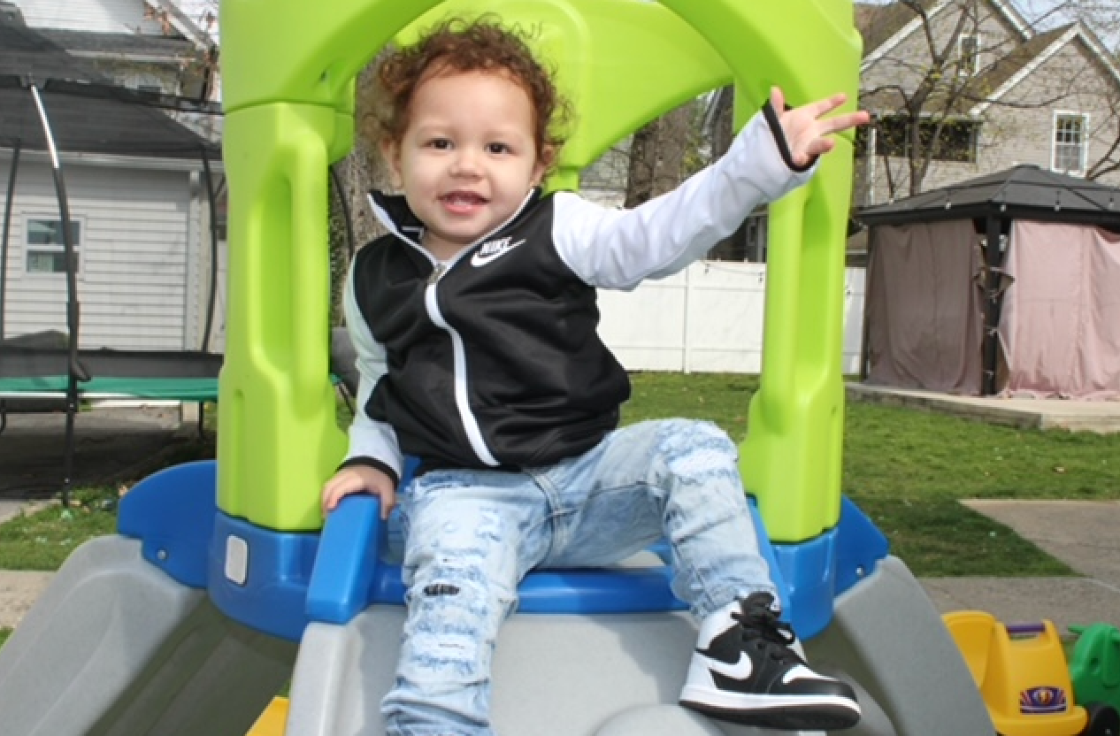 A little boy is sitting on top of a slide.