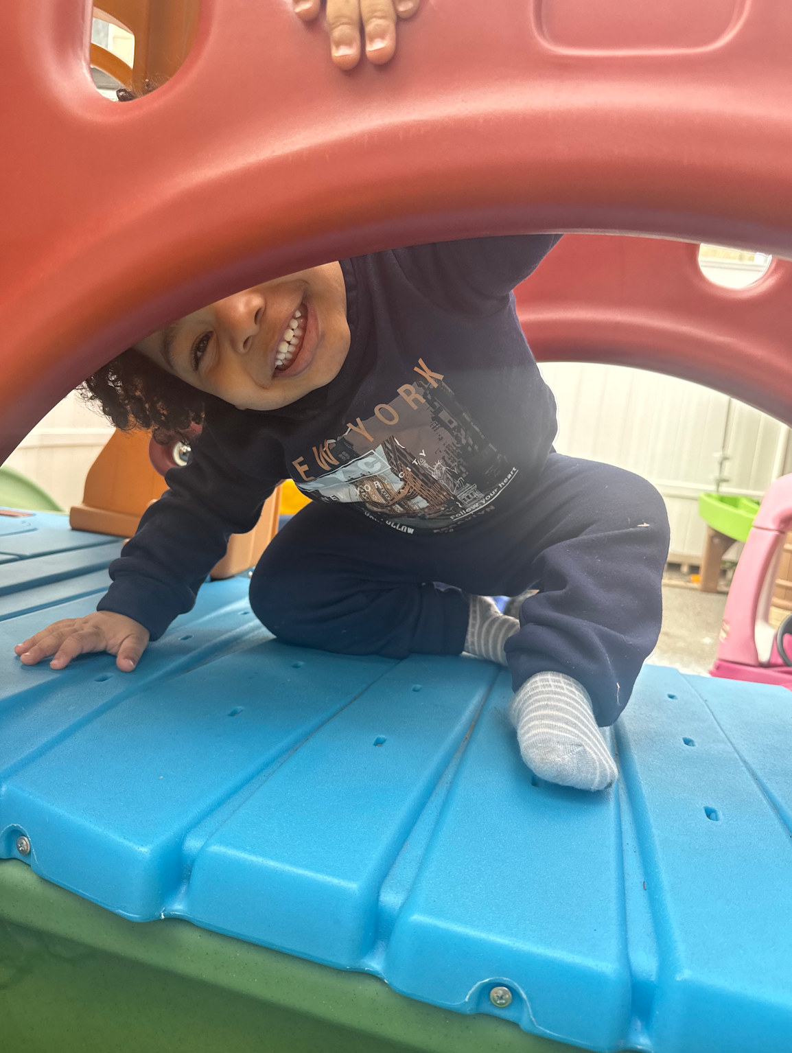 A little boy is playing on a playground and smiling.