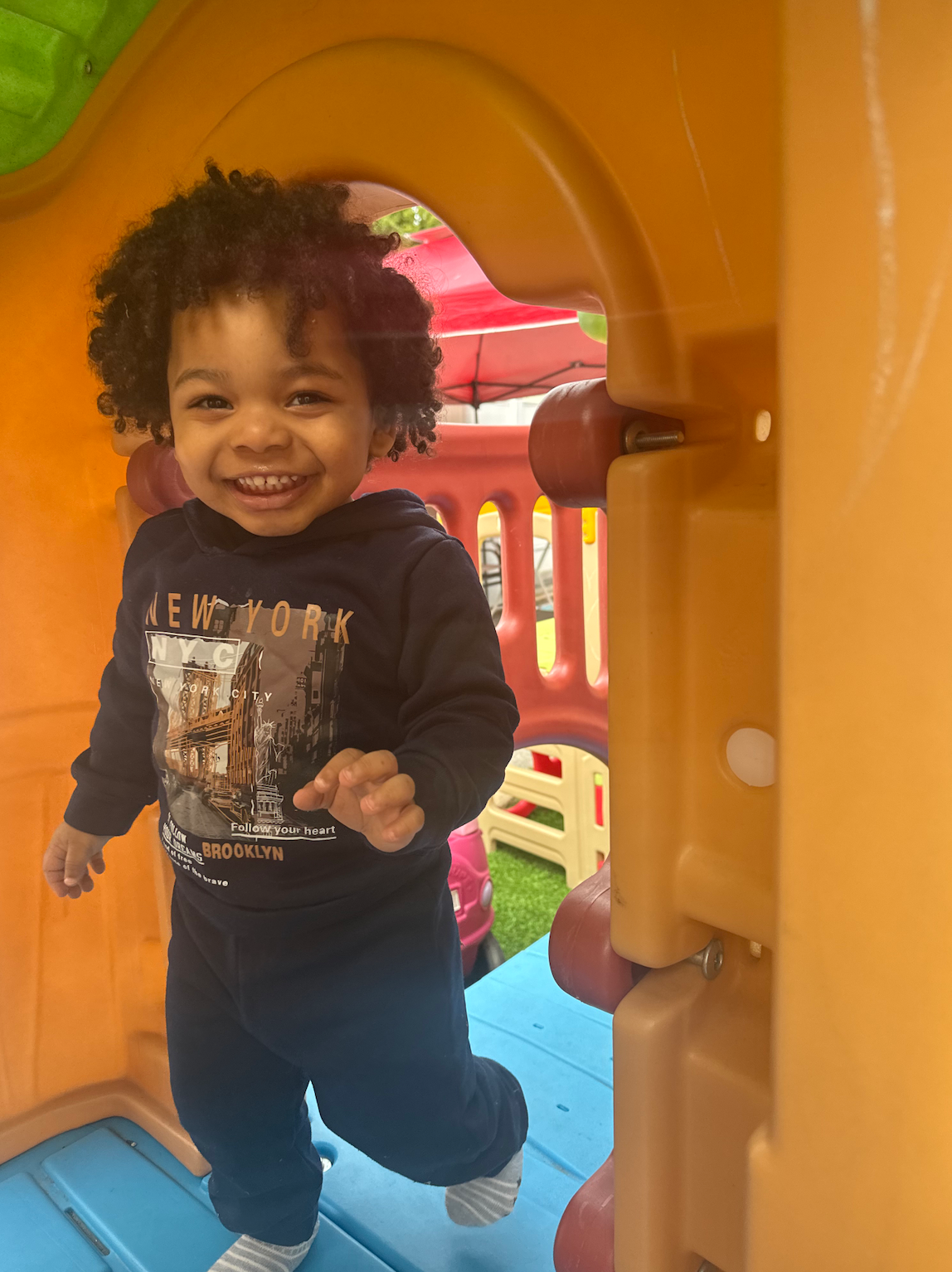 A little boy wearing a new york shirt is playing in a playground