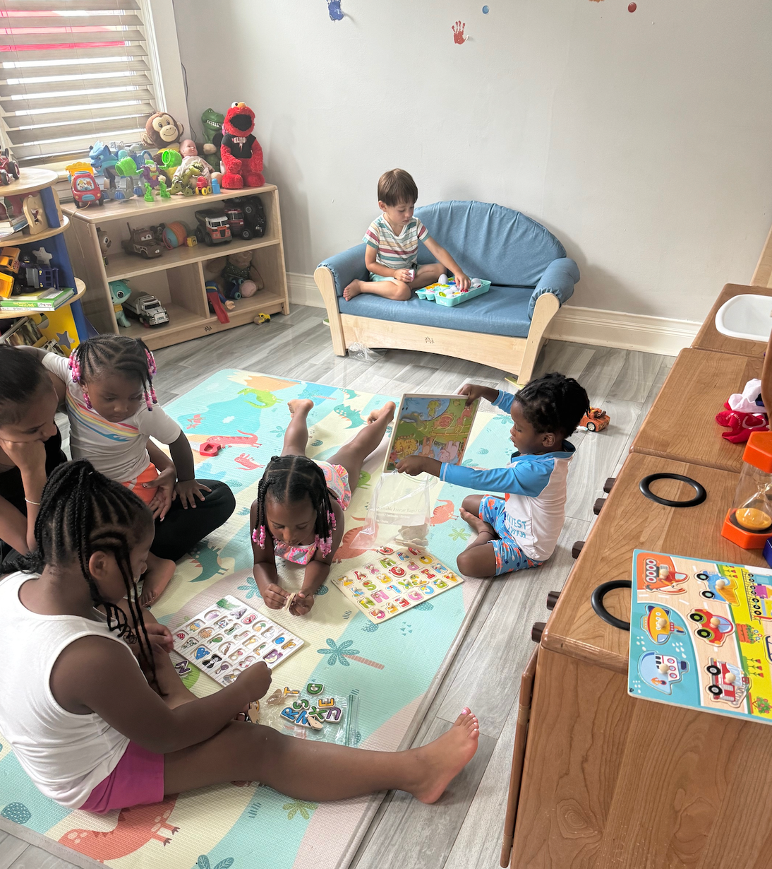 A group of children are sitting on the floor in a play room.
