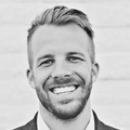 A man with a beard is smiling in a black and white photo.