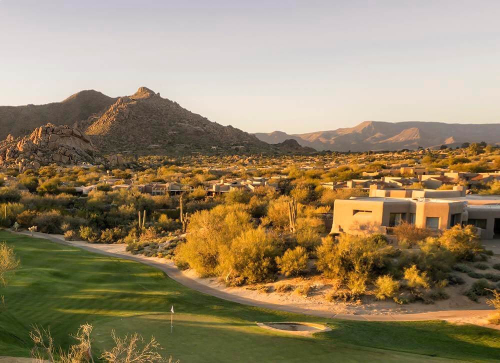 A golf course in the desert with mountains in the background.