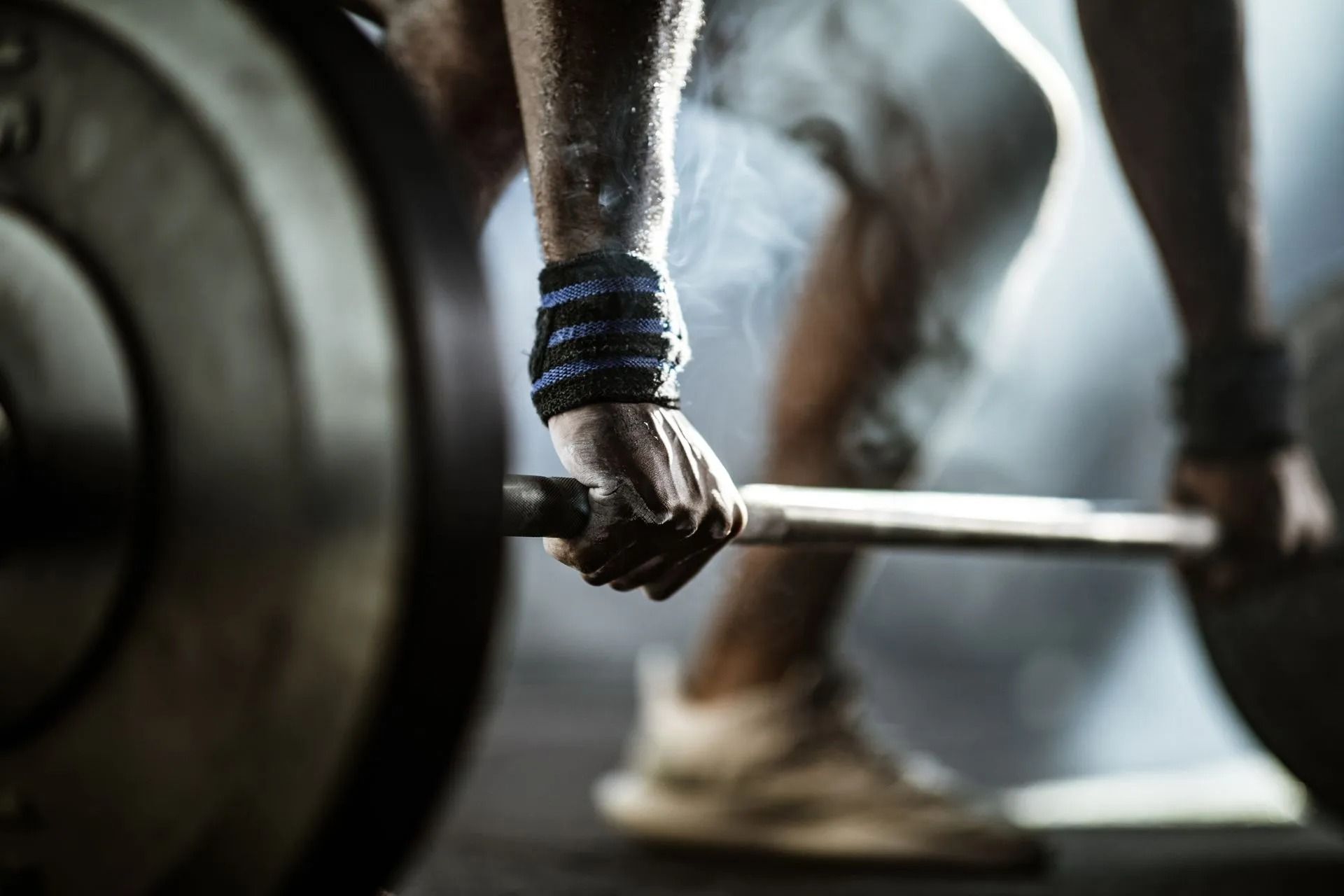 Close-up of a weightlifter gripping a loaded barbell in a gym.