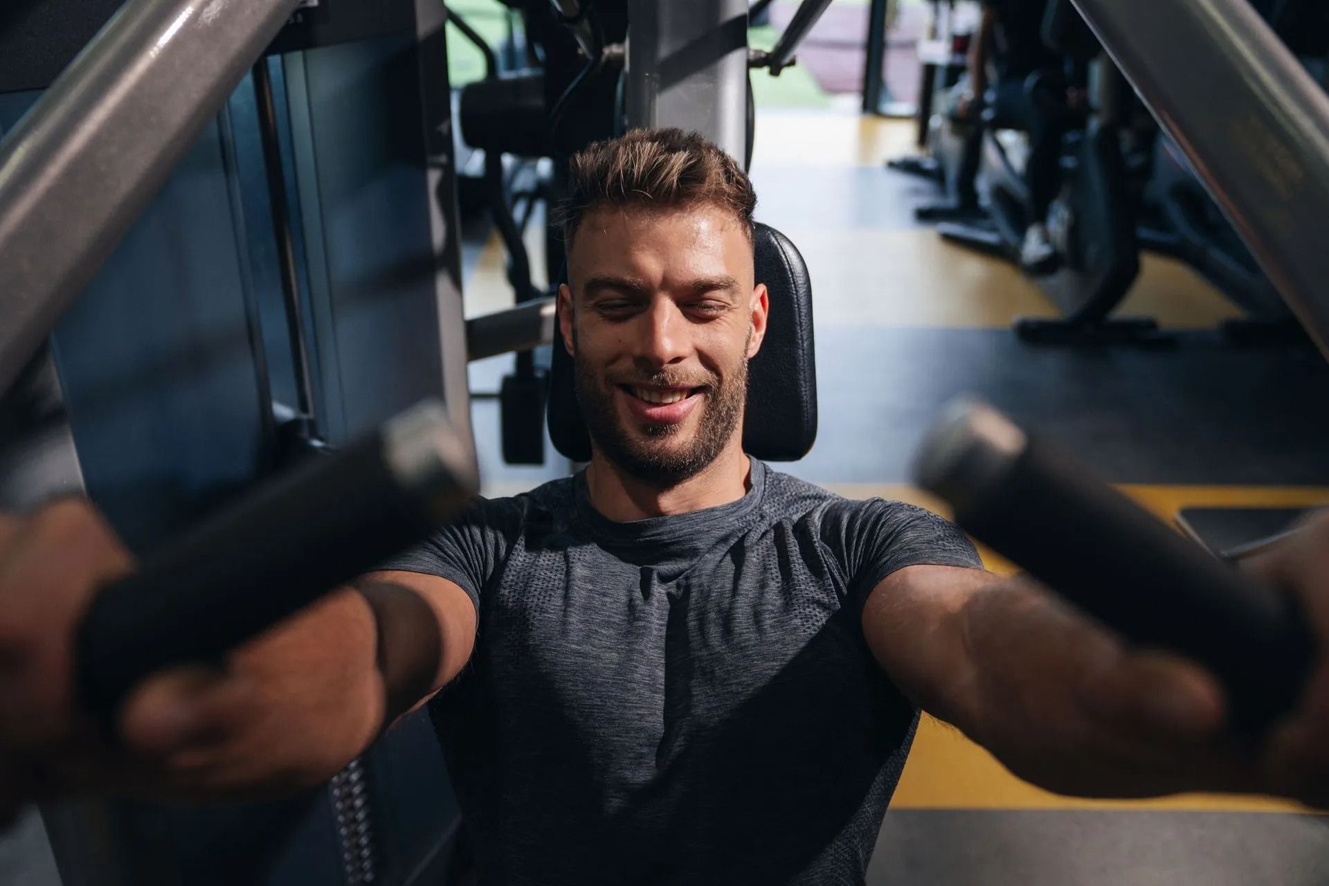 Man using a chest press machine in a gym, smiling during a workout