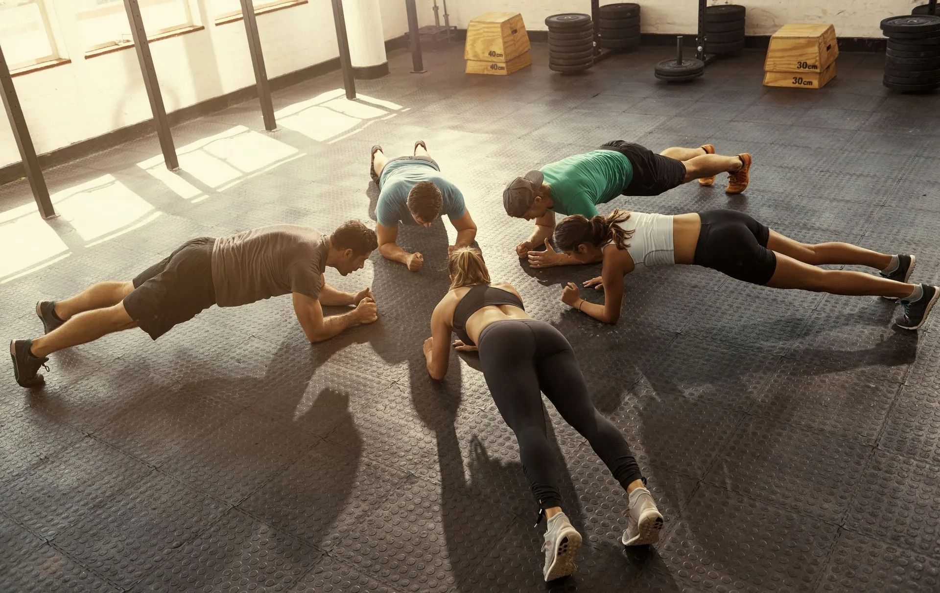 People doing a group plank workout on a gym floor