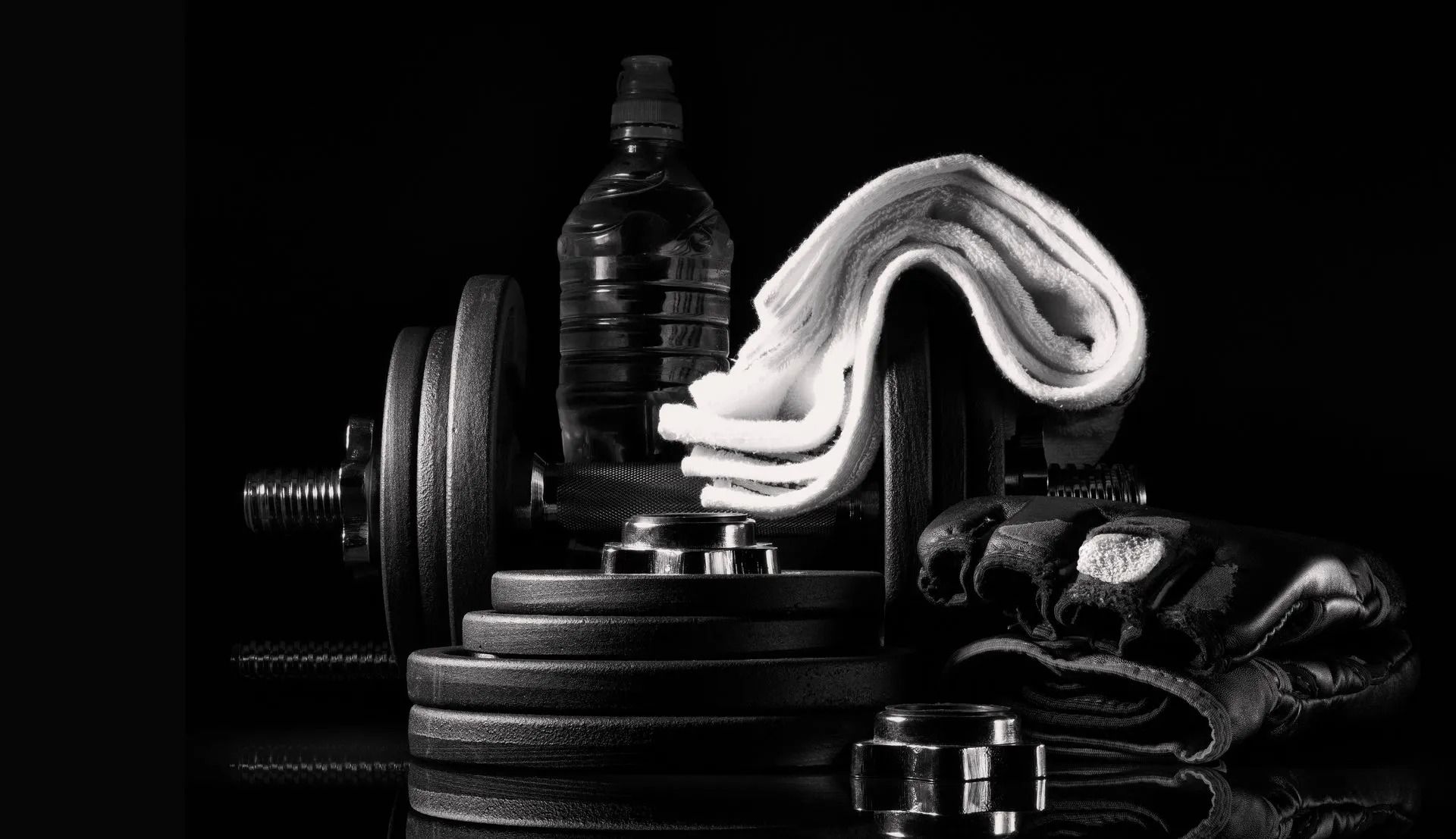 Gym equipment with a water bottle and white towel on a black background