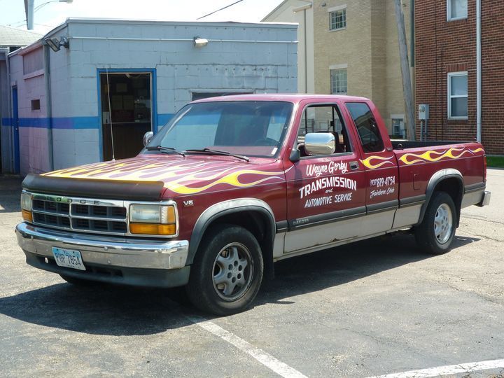 Red and silver pickup truck with flame decals parked outside a building.