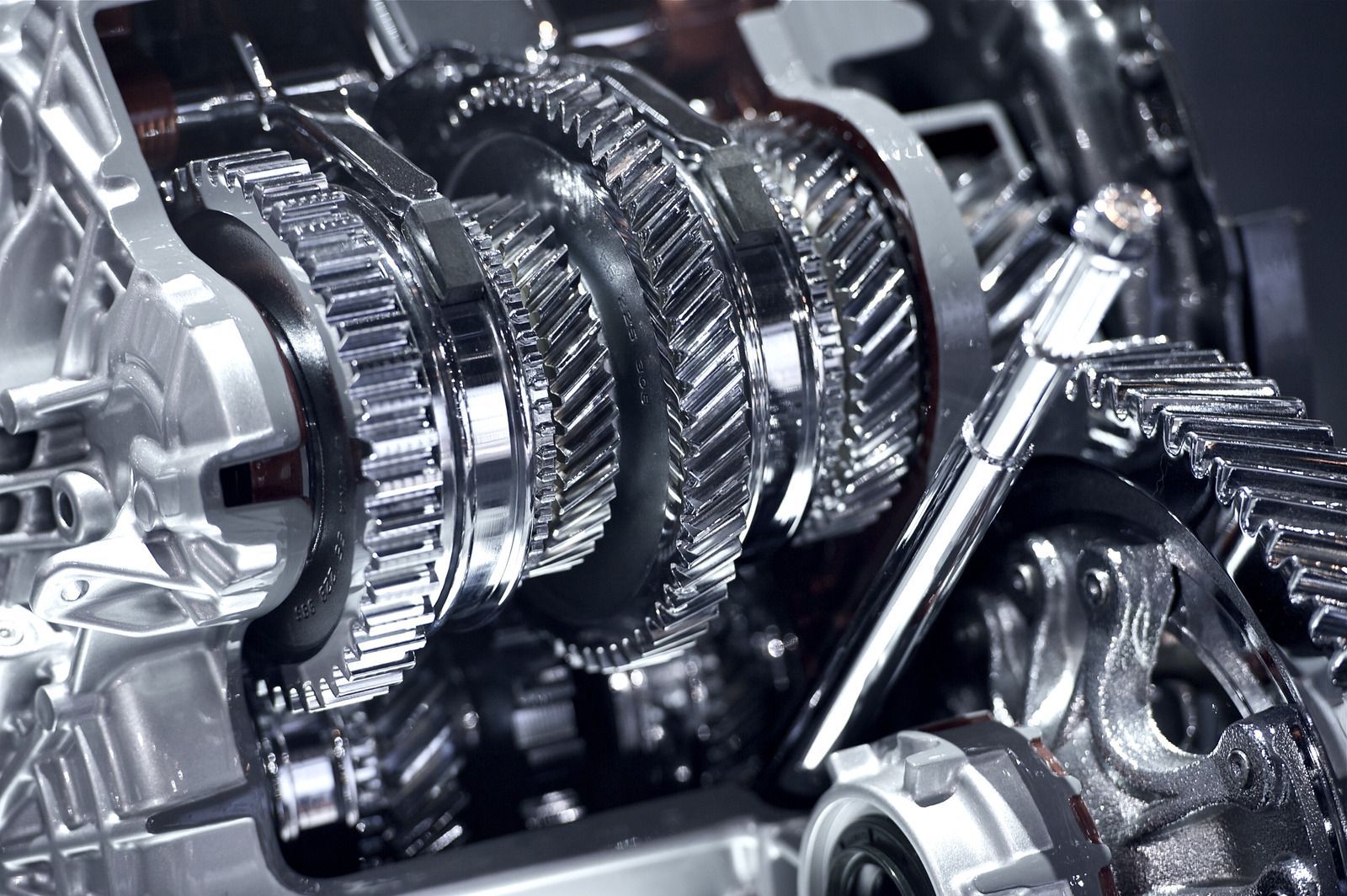 Close-up of a cutaway car transmission showing interlocking gears in polished metal.