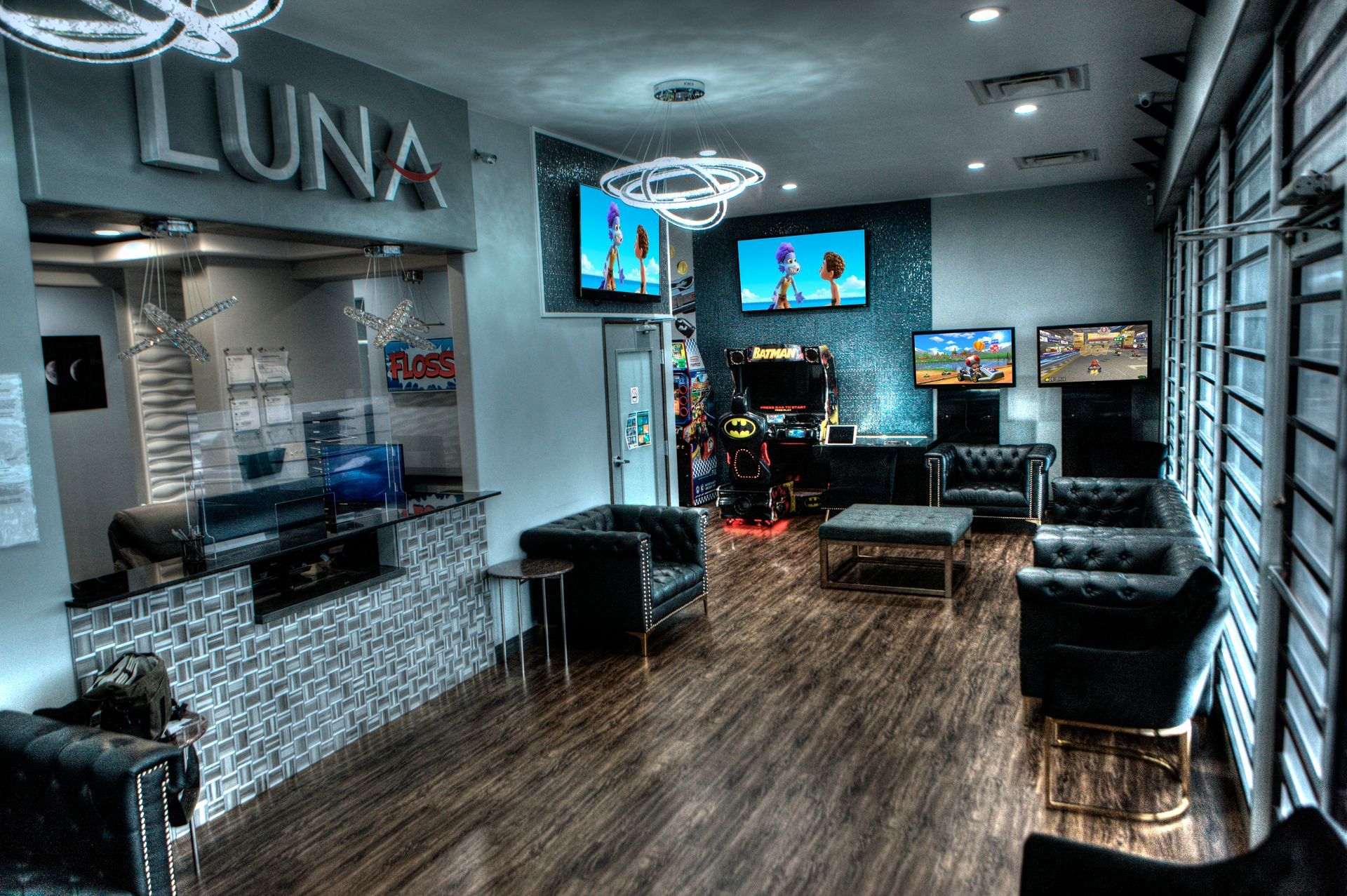 Luna-Dental-Dallas- Interior of a business called Luna. Reception desk, lounge seating, video games, and TVs are visible.