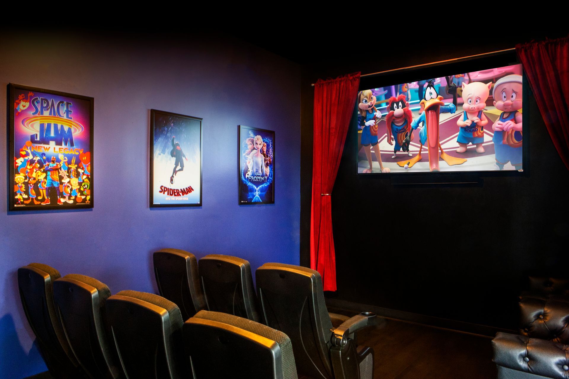 Luna-Dental-Dallas- Movie theater with Space Jam poster, screen displaying animation, red curtains, and seating.