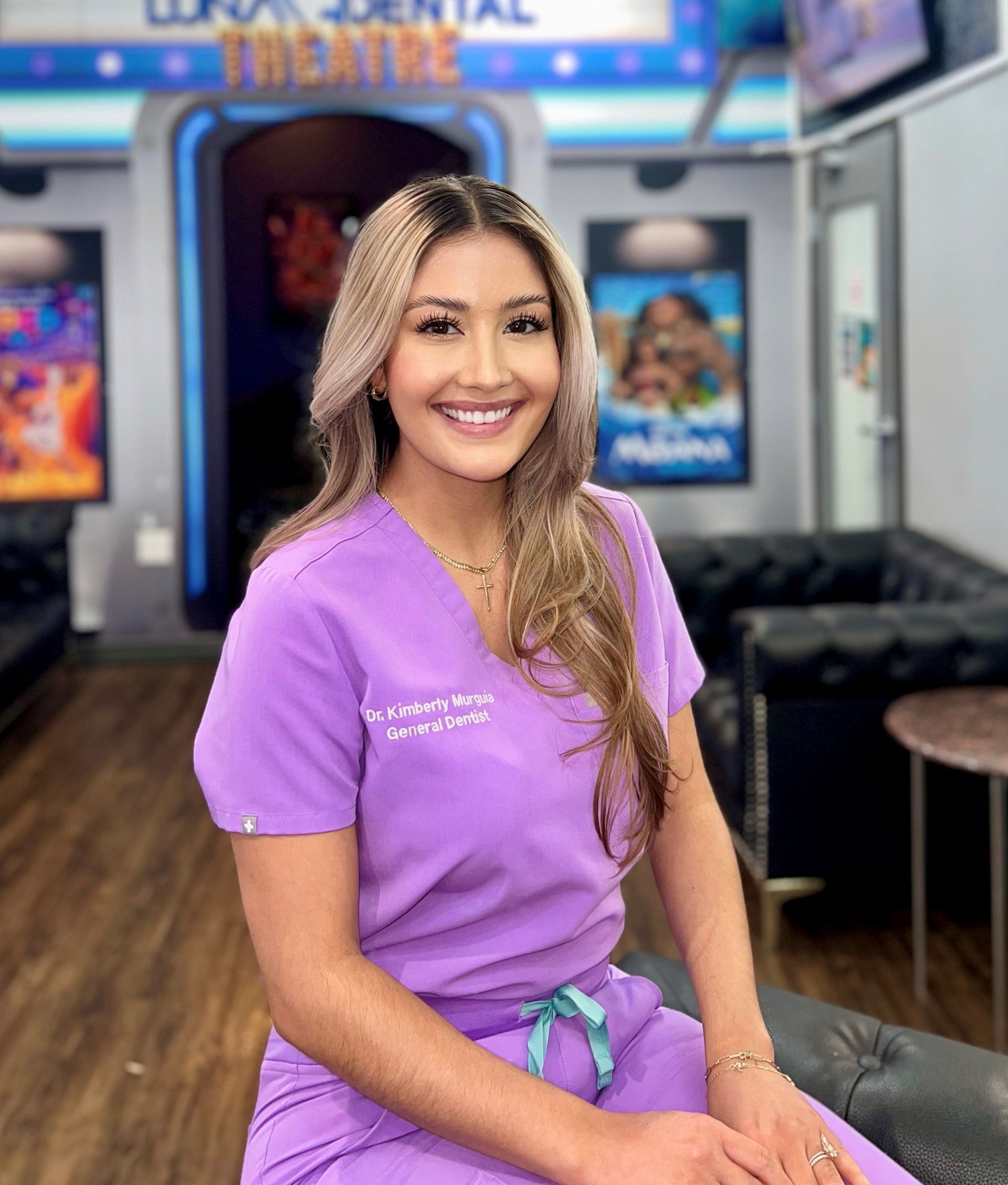 Luna-Dental-Dallas- Woman in purple scrubs smiles in a dental office.