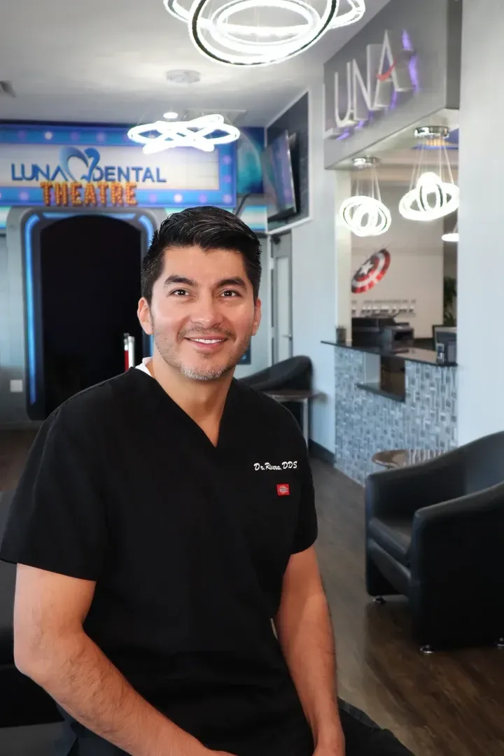 Luna-Dental-Dallas- Man in black scrubs smiles in a dental office.