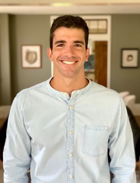 Luna-Dental-Dallas- Smiling man in a light blue button-up shirt, standing indoors with artwork on the wall.
