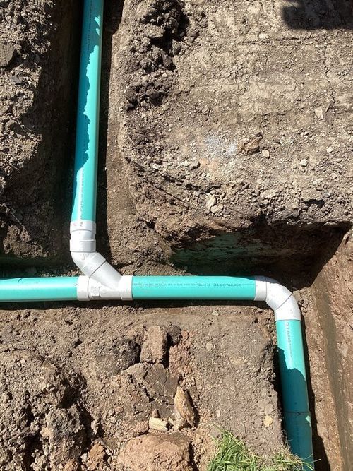A close up of a green pipe in the dirt